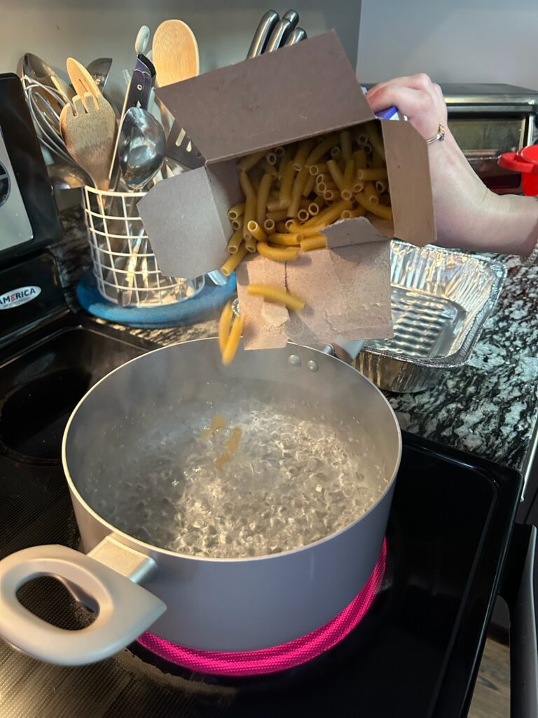 Ziti pasta poured into pot of boiling water