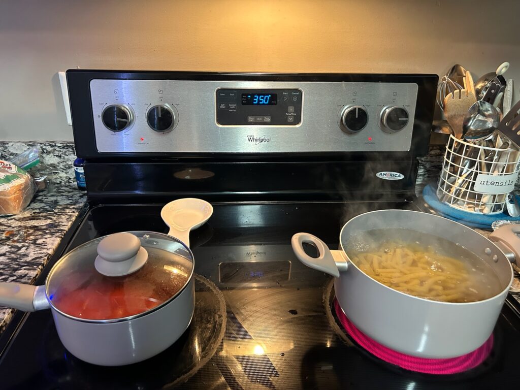 Tomato sauce is simmering while pasta is cooking