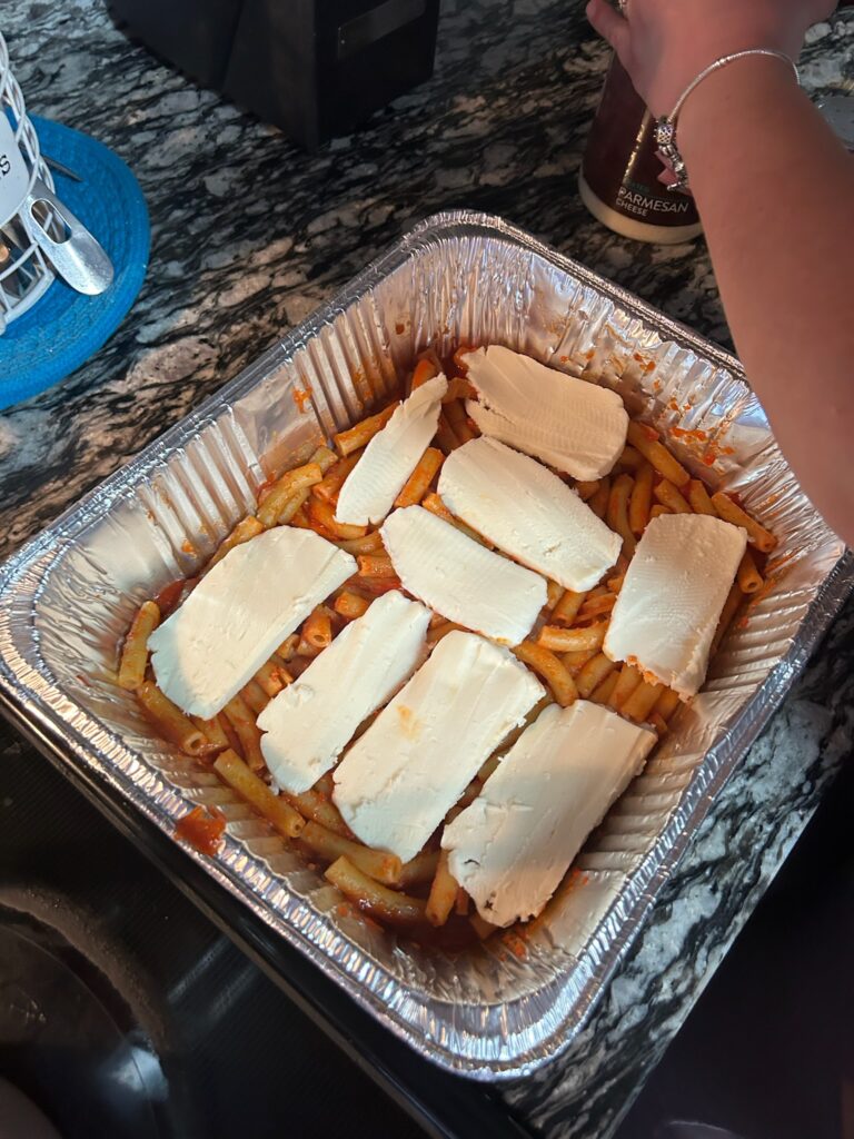 Cheese being placed on top of ziti